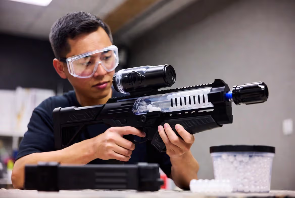 Person preparing gel blaster and putting on safety goggles