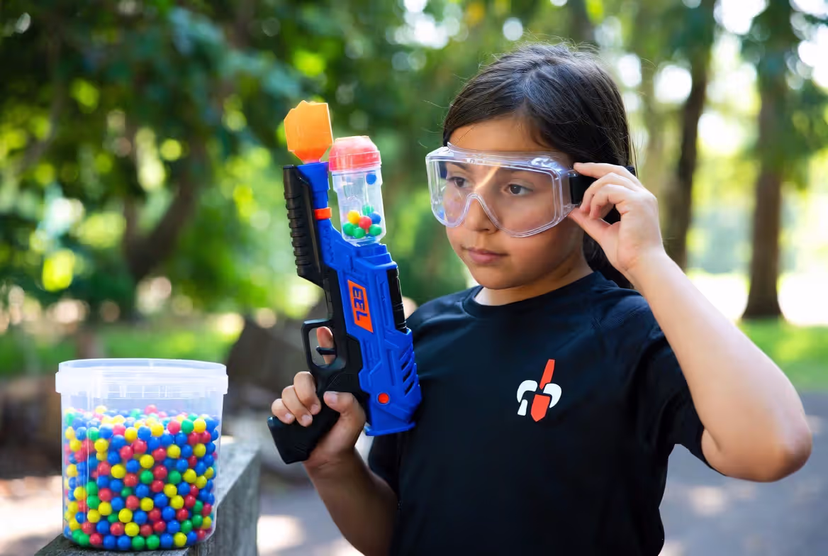 Person preparing gel blaster and putting on safety goggles before play