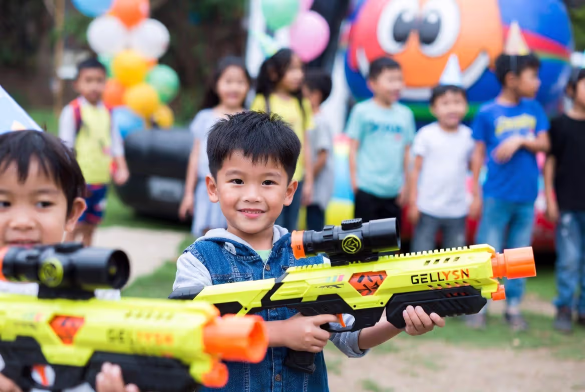 Child celebrating birthday with gellyball game holding blaster
