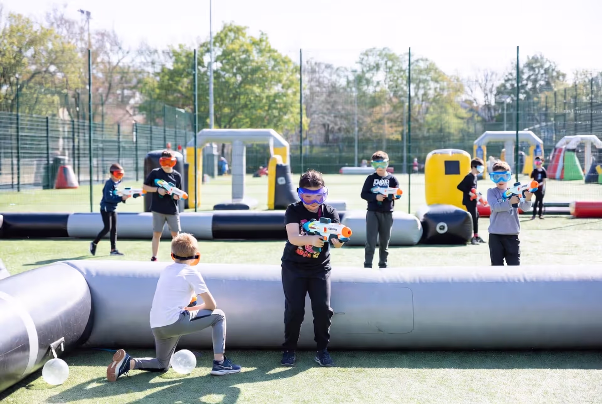 Kids and parents playing gellyball game with inflatable obstacles outdoors