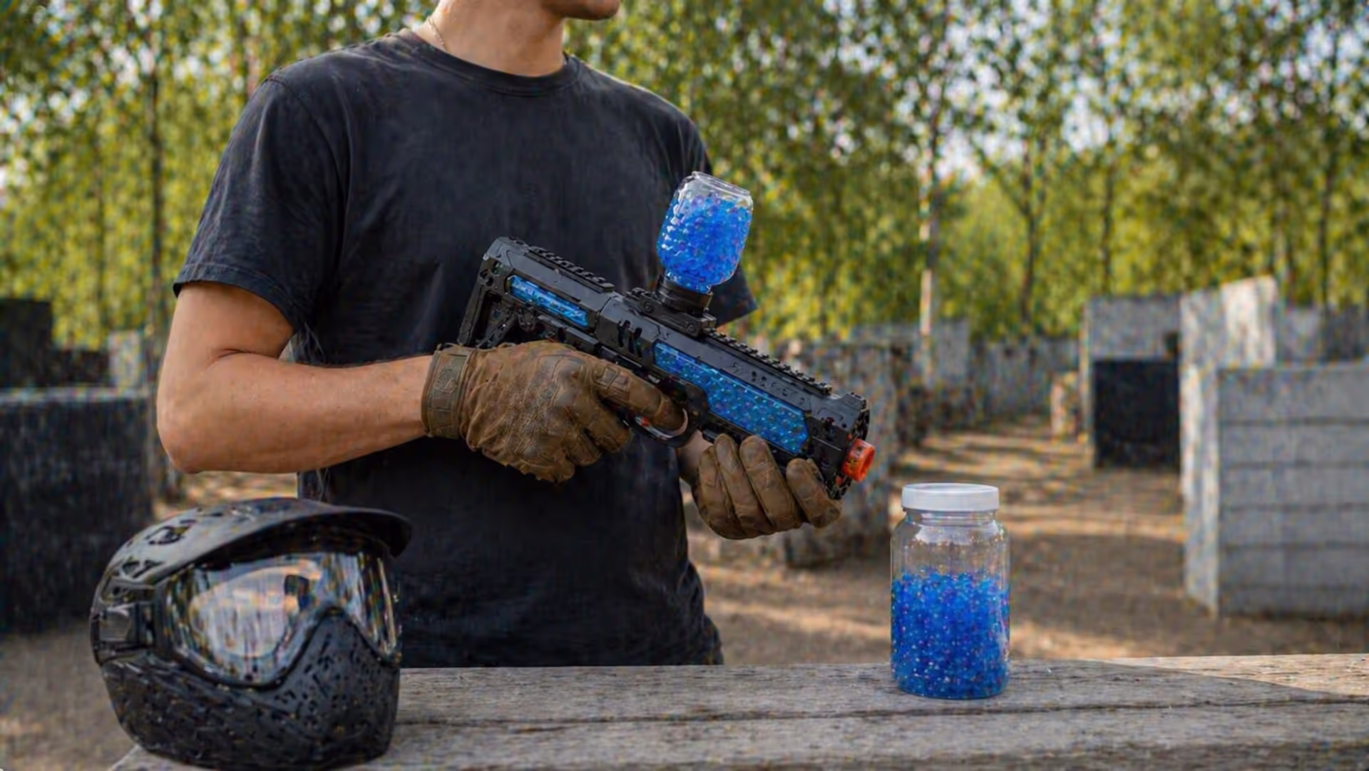 Person holding gel blaster with ammo and safety goggles outdoors