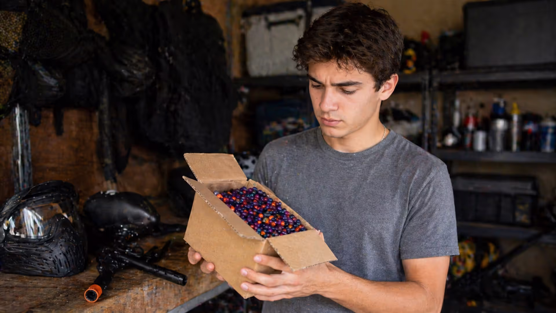 person holding box of paintballs in storage and checking condition